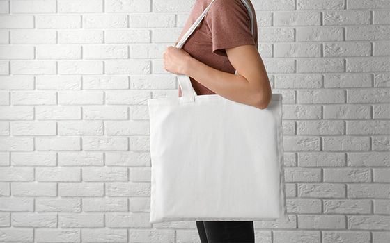 Person carrying bag against white brick background