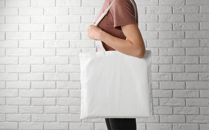 Person carrying bag against white brick background